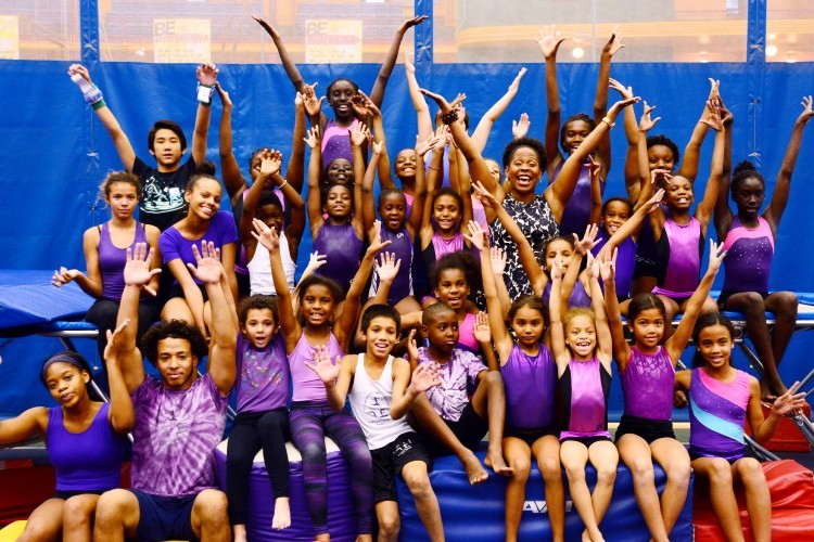 team of children with arms raised and smiling in gymnastics outfits