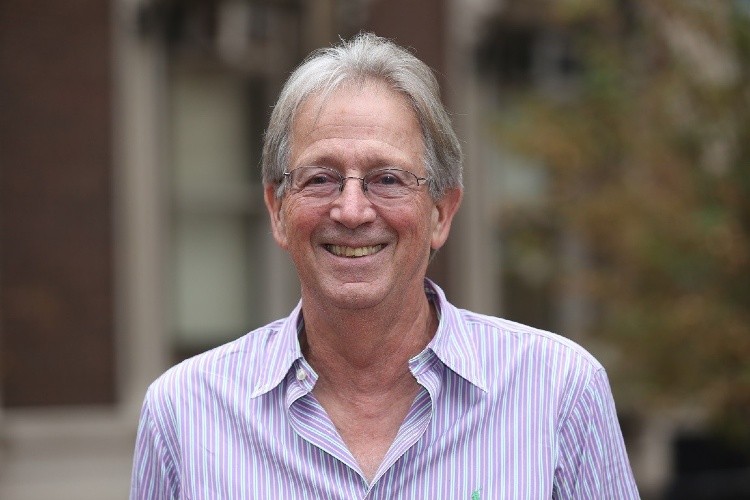 Photo of man in slightly unbuttoned collared shirt smiling