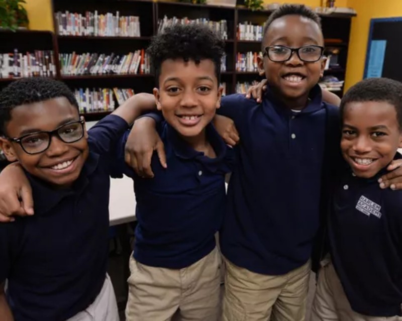 four young children smiling for a group photo in school uniforms