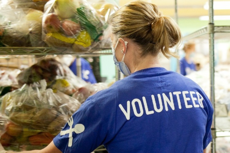 CCS Grantee: New York Common Pantry Back of person facing bags of food, their shirt says volunteer.