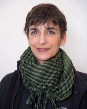 A headshot of a woman with short hair wearing a scarf.