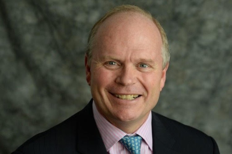 Scott Wright A headshot of a blond man in a pink shirt and black jacket smiling at the camera.