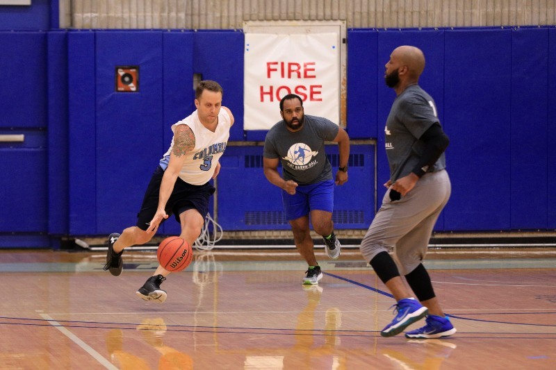Columbia staff compete in the CCS Basketball Tournament (Photo credit: Eileen Barroso) Three men playing basketball, with one dribbling past another.