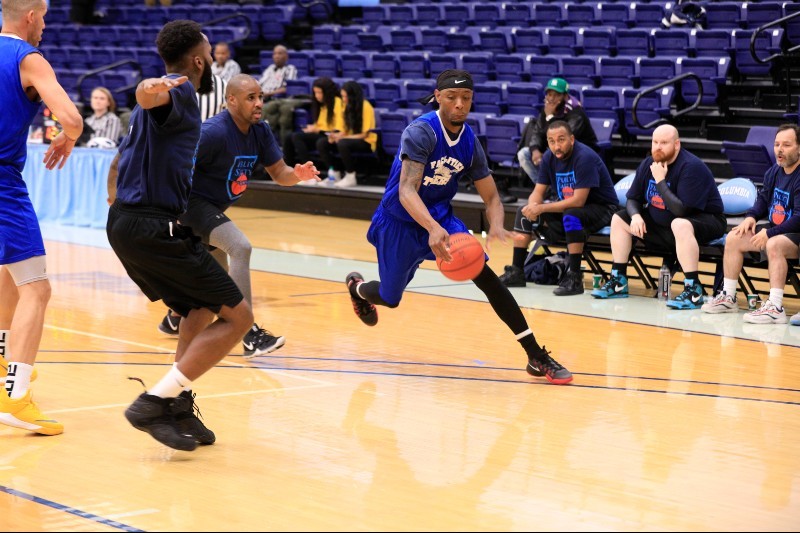 A player dribbles a basketball past another player guarding him.